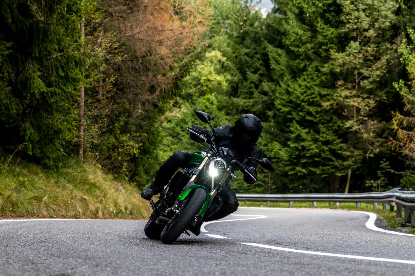 Grünes Benelli Motorrad in Kurvenfahrt auf einer Waldstrasse
