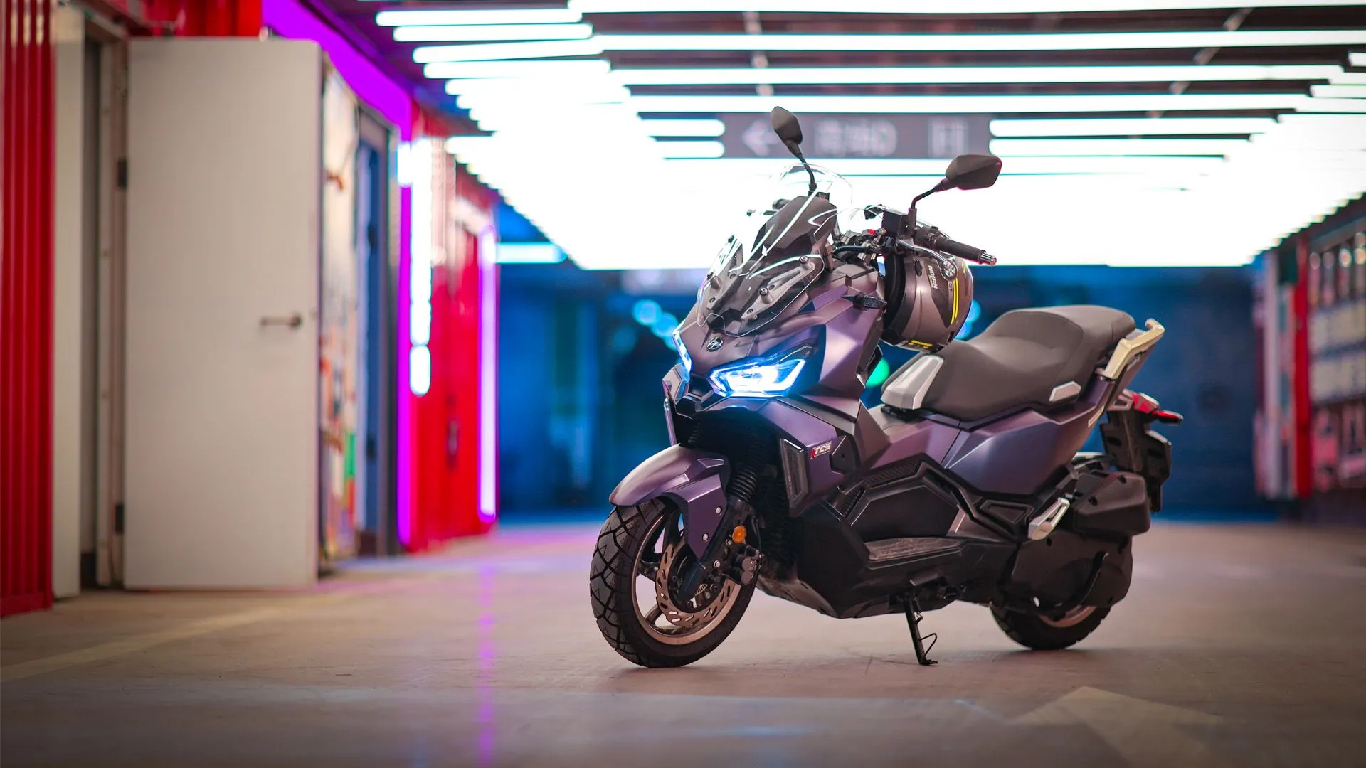 Violetter SYM Maxi-Roller in einer beleuchteten Neon-Garage